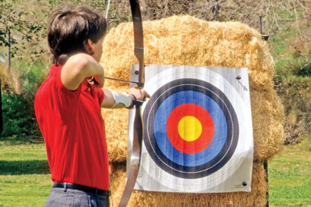 Archer aiming bow and arrow at target