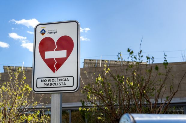 Barcelona, Spain - April 2, 2023. A stark road sign stands against a bright sky, warning of the dangers of gender-based violence in an effort to guide and communicate with viewers.