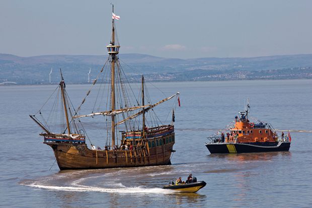 A stranded galleon is approached by a tugboat