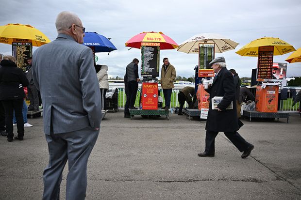 Racegoers walk past bookmakers' betting stands on the final day of the Grand National Festival horse race meeting, illustrating the low success rates for some UK research council grant schemes.