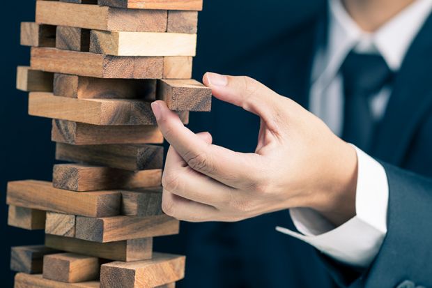 Businessman carefully removing wooden block from tower