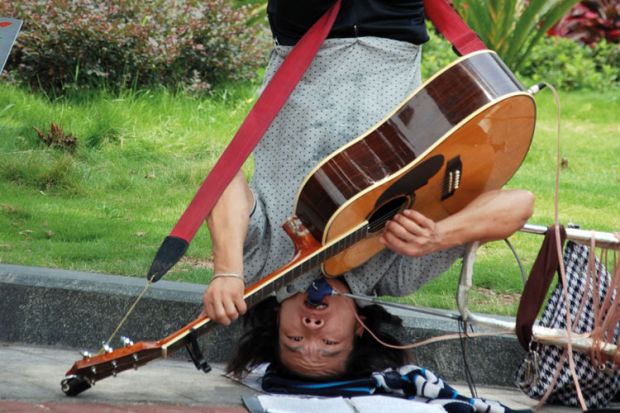 Busker playing guitar upside-down