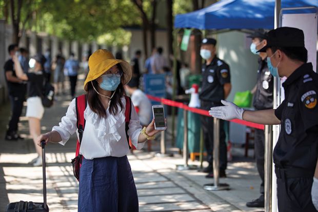 Student in mask shows mobile phone to health check in Wuhan, China