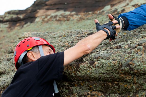 Climber being helped to climb mountain