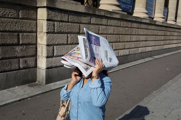 Woman covers her face with paper