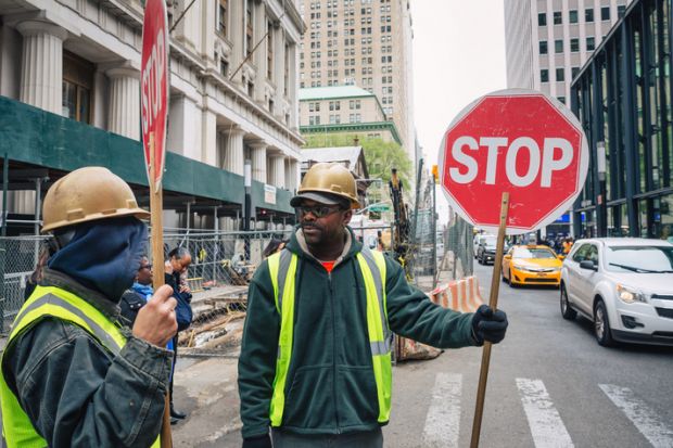 A minority ethnic man with a sign to stop traffic