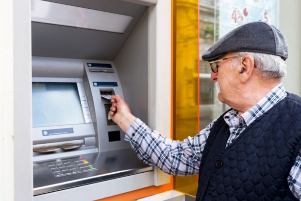 Elderly man inserting credit card to ATM
