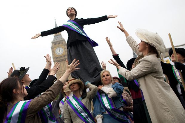 Feminists dressed as The Suffragettes at a protest for women's rights in London. One is standing on the others. To illustrate how a boycott of a feminist title failed to consider its likely impact on early career researchers