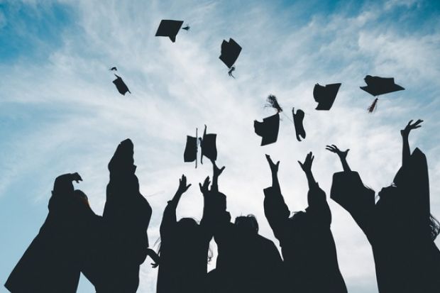 Graduates throw their caps into the air, symbolising the graduate premium