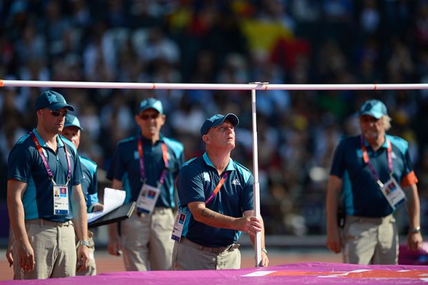 An official is setting the bar during the women's high jump at the London 2012 Olympic Games, illustrating that the UK government is expected to resist pressure to set an ambitious new target for international student numbers.