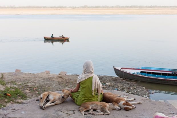 Scarfed young indian woman meditating on the border of the Ganges 