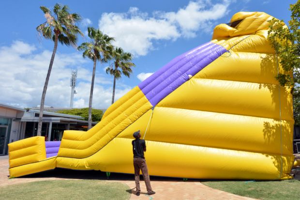 Gold Coast, Australia - October 19, 2014: Worker inflates a slide bouncy castle.