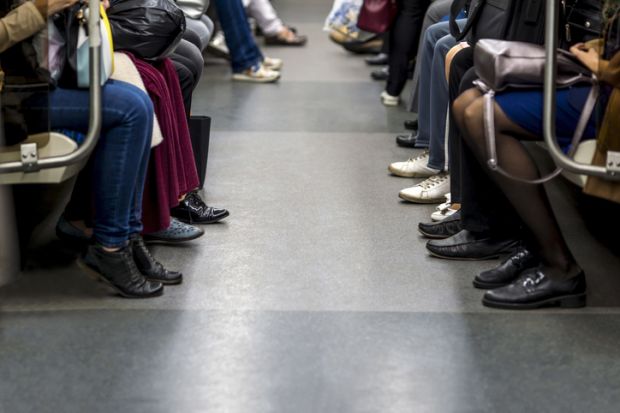 Feet of people sitting opposite each other in a subway car.