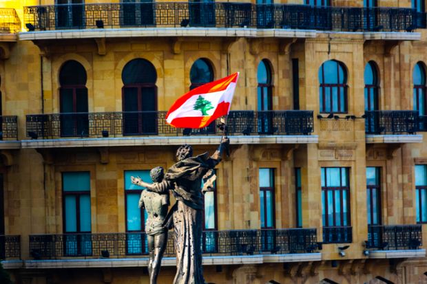 A statue of two people hugging with a Lebanese flag attached