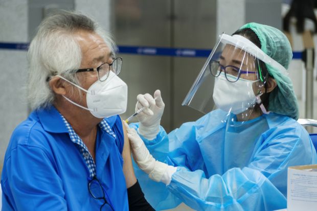  doctor or nurse giving covid antivirus vaccine shot to senior man patient wearing protective face mask