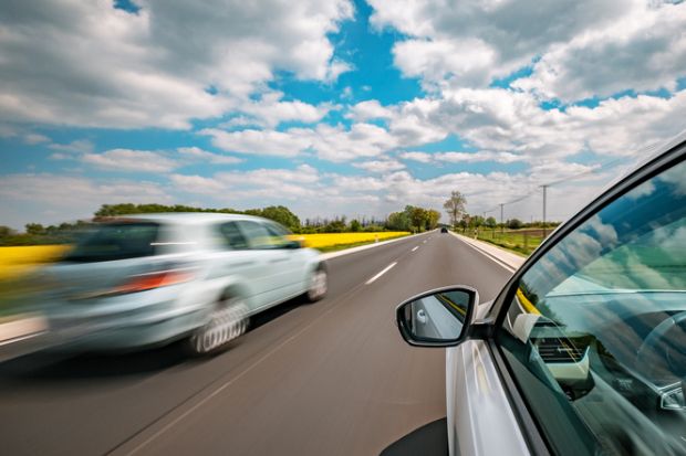 One silver car overtakes another