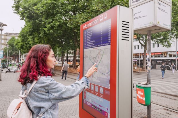 Oman passenger using digital touch-screen terminal display with information about bus and train routes