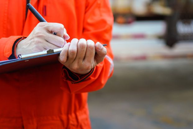 Close-up of some hands holding a clipboard and writing something