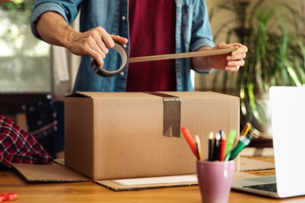 A man puts some tape onto a cardboard package