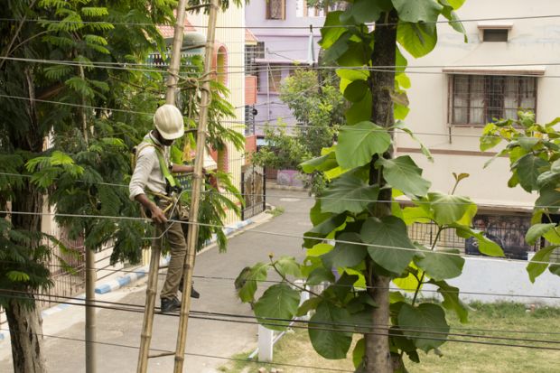 Kolkata electricity supply worker doing maintenance work on overhead electric cable