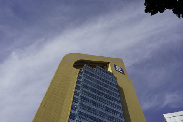 ASEEC Tower Airlangga University, a blue and gold tall building seen from below with clear sky.
