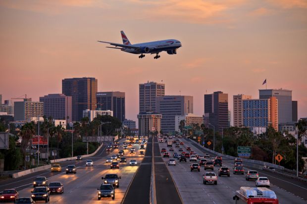  British Airways Boeing 777 flying over crowded freeway to land at Lindberg Field San Diego International Airport.