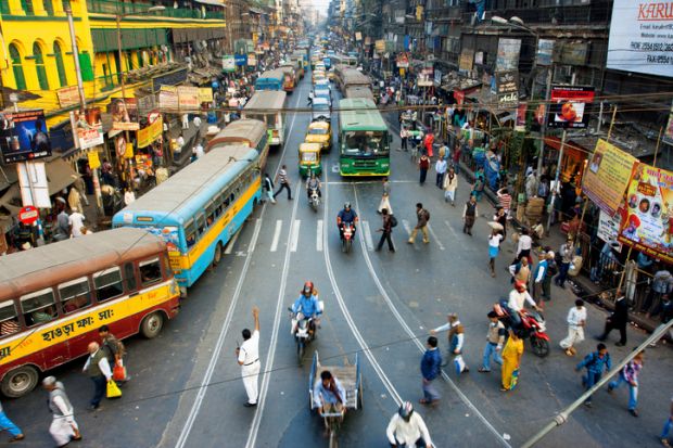 Pedestrians cross the road in front of motorcycles, cars and buses at the crossroads on January 20, 2013 in India.