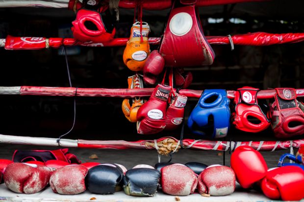 Boxing gloves hang off a boxing ring