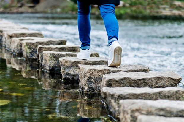 Woman crossing stepping stones on a river