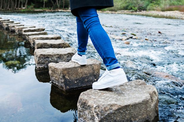 Person walks across stepping stones