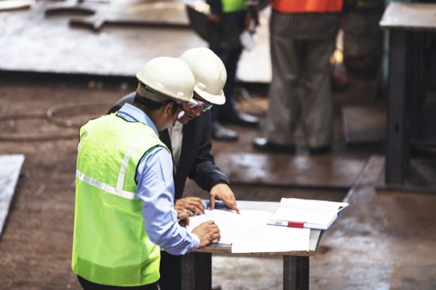 Factory owner deciding on the potential to improve his factory with the engineers, ready with his pen in hand