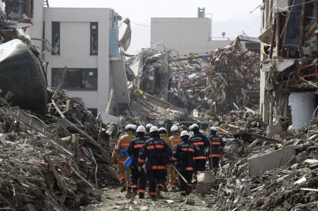 Rescue Team searching operation on debris and mud covered at Tsunami hit Destroyed city in Rikuzentakata on March 20, 2011, Japan.