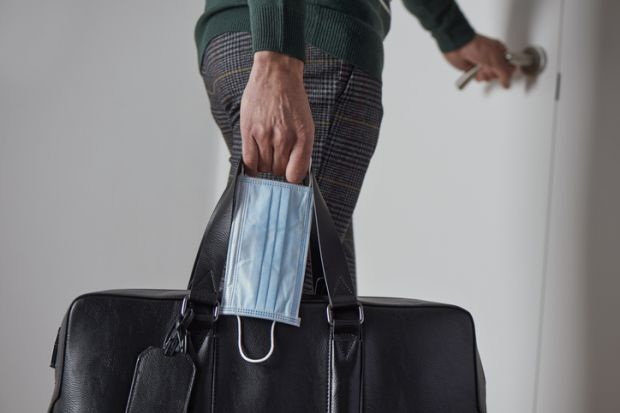 A man leaves home with a suitcase and a surgical mask