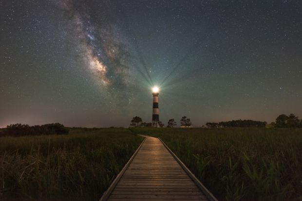 A lighthouse shines at night, illustrating community engagment