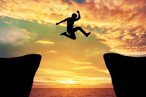 Man jumping between rocks against sunset