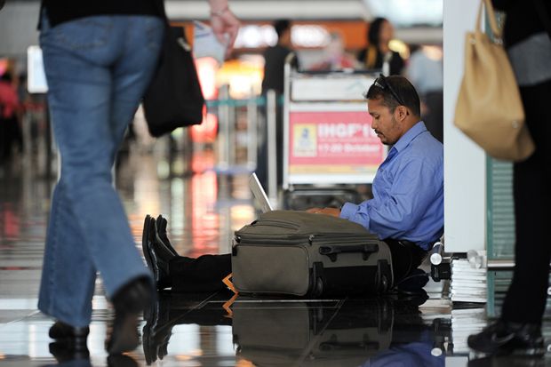 A man uses his laptop while waiting at Hong Kong's international airport, illustrating that many PhD applicants have been left in limbo after a computer glitch affected their application for an Australian visa.