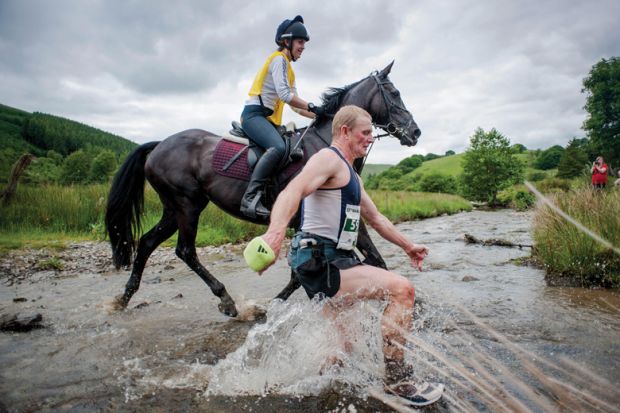 Man racing horse across shallow river