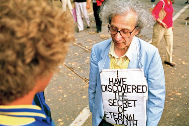 Man wearing 'I have discovered the secret of eternal youth' sign