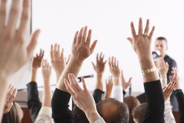 People raise their hands in a meeting, illustrating no-confidence votes