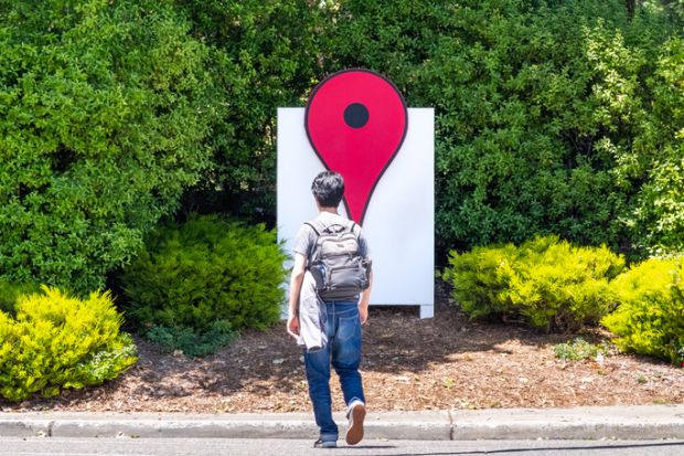 Person walking in front of the Google Maps Icon