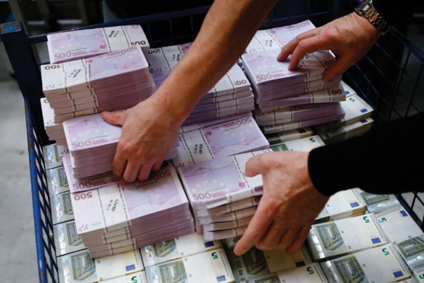 Piles of euro banknotes being counted and stacked