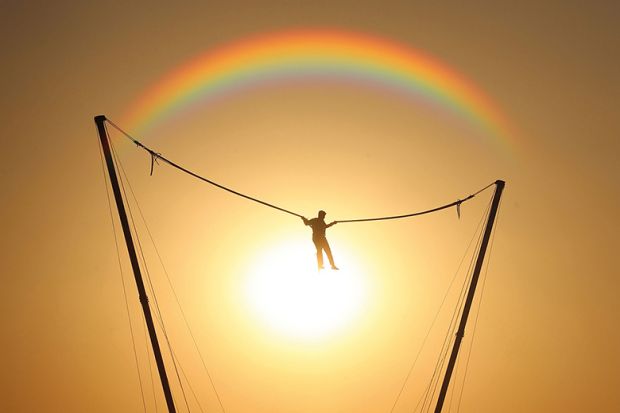 person bouncing in front of rainbow