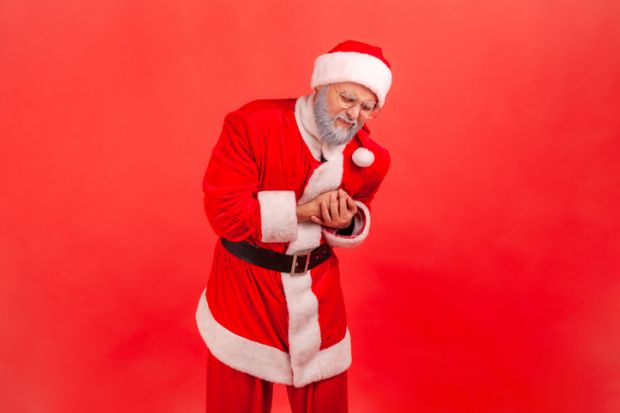 A man in a santa claus costume holding his chest and grimacing