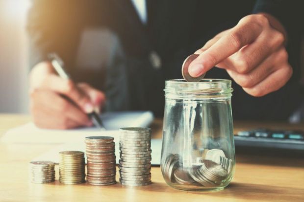 putting coins in a jar representing college and university fees