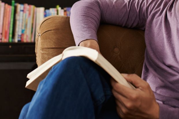 Seated man on sofa reading book