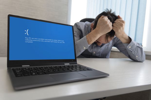 showing error blue screen on the Laptop against the background of an angry upset man clutching his head