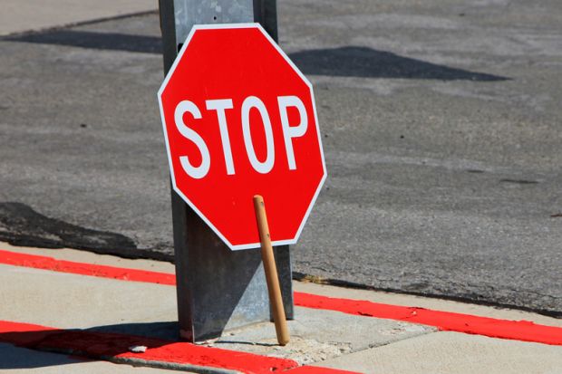 Stop sign rested against street sign pole