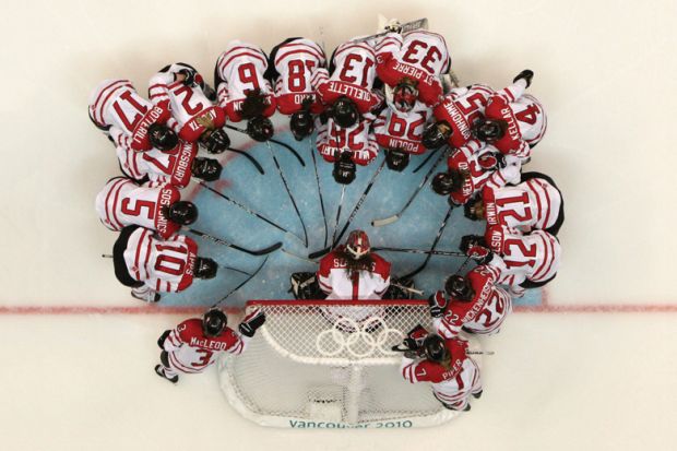 Team Canada in huddle on rink, Winter Olympic Games, 2010