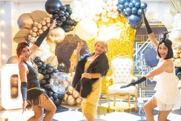 Three women in vintage 1920s attire dancing at a Gatsby-themed celebration.