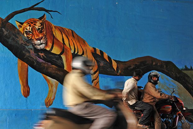 Commuters drive past a mural of a resting tiger, India. Illustrating that the ambitious goals of the Institutes of Eminence programme have yet to be realised.